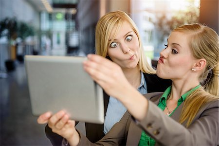 simsearch:614-06896571,k - Two young businesswomen pulling faces and taking selfie on digital tablet in office Fotografie stock - Premium Royalty-Free, Codice: 614-07735349