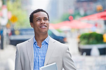 street businessman walking - Young businessman walking on city street carrying digital pad Stock Photo - Premium Royalty-Free, Code: 614-07735451