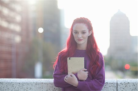 Portrait of pink haired young woman with notebook on city rooftop Stock Photo - Premium Royalty-Free, Code: 614-07735488