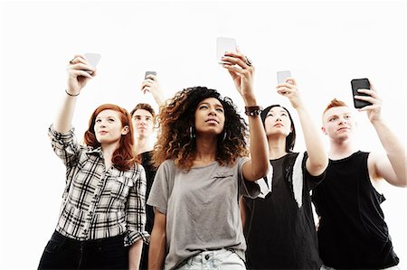 Studio portrait of five young adults taking selfies on smartphones Stock Photo - Premium Royalty-Free, Code: 614-07735557