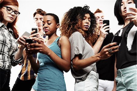 simsearch:614-07735586,k - Low angle studio shot of six young adults texting on smartphone Foto de stock - Sin royalties Premium, Código: 614-07735566