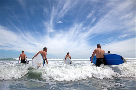 rivals - Group of male and female surfer friends wading into sea with surf boards Stock Photo - Premium Royalty-Free, Code: 614-07767978