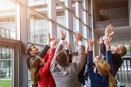 Group of businesswomen and men raising hands together in a circle Stock Photo - Premium Royalty-Free, Code: 614-07768119