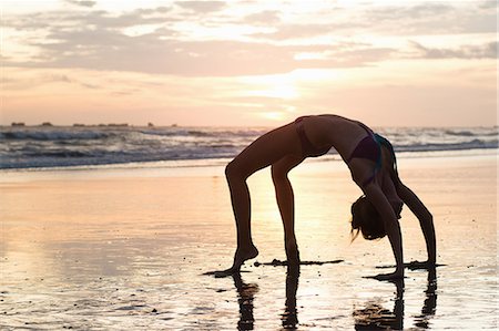 Mid adult woman bending over backwards on beach at sunset, Nosara, Guanacaste, Costa Rica Stock Photo - Premium Royalty-Free, Code: 614-07768218