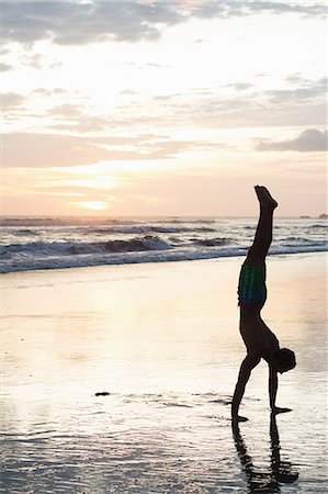 Young man doing handstand on beach at sunset, Nosara, Guanacaste, Costa Rica Stock Photo - Premium Royalty-Free, Code: 614-07768219