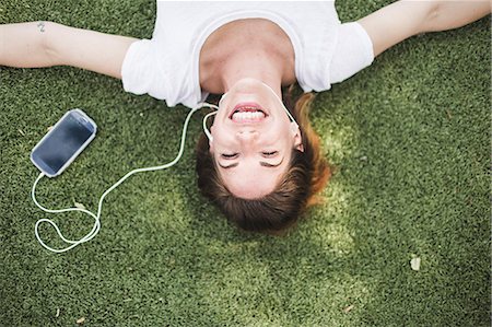 Overhead portrait of mid adult woman listening to earphones in park Stock Photo - Premium Royalty-Free, Code: 614-07768235