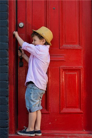 Boy opening red front door Stock Photo - Premium Royalty-Free, Code: 614-07768245