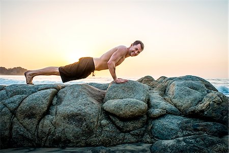 simsearch:614-07768262,k - Mid adult man doing push-ups on rocks at beach Foto de stock - Sin royalties Premium, Código: 614-07768254