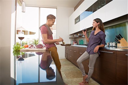 drinking luxury - Couple chatting and drinking wine whilst cooking in kitchen Foto de stock - Sin royalties Premium, Código: 614-07805764