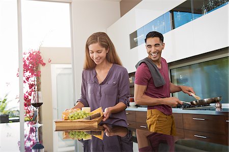 Couple preparing cheeseboard and cooking in kitchen Stock Photo - Premium Royalty-Free, Code: 614-07805763