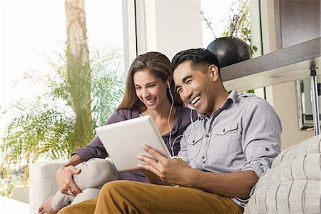 Couple on sitting room sofa looking at digital tablet Stock Photo - Premium Royalty-Free, Code: 614-07805774