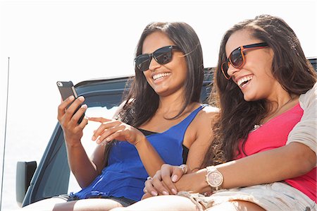 roadtrip vacation - Two young women sitting on jeep hood looking at smartphone Stock Photo - Premium Royalty-Free, Code: 614-07805805