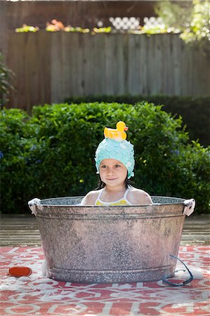 Portrait of girl in bubble bath in garden with rubber duck on head Stock Photo - Premium Royalty-Free, Code: 614-07805878