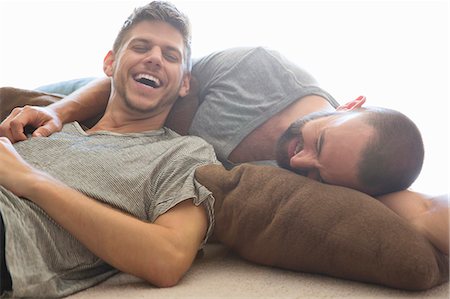 Male couple reclining and laughing on sitting room floor cushions Foto de stock - Sin royalties Premium, Código: 614-07805895