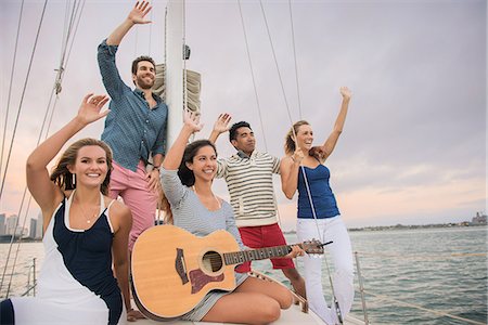 sailing music - Friends on sailing boat waving, woman with guitar Stock Photo - Premium Royalty-Free, Code: 614-07805988