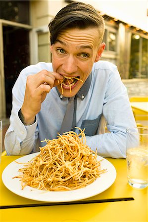 french fry smile - Young man eating skinny french fries at sidewalk cafe Stock Photo - Premium Royalty-Free, Code: 614-07806193