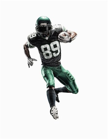 Studio shot of young male football player running with ball Stock Photo - Premium Royalty-Free, Code: 614-07806238