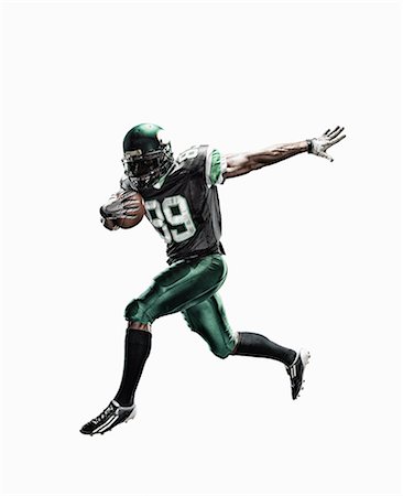 Studio shot of male football player running with ball Stock Photo - Premium Royalty-Free, Code: 614-07806239