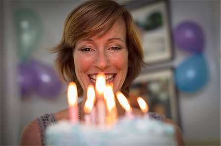 Mature woman holding birthday cake with candles Stock Photo - Premium Royalty-Free, Code: 614-07806337