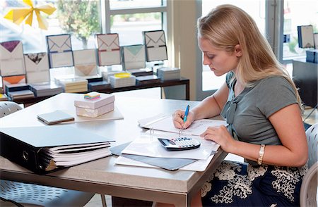 people sitting on desk - Female sales assistant doing paperwork in stationery shop Stock Photo - Premium Royalty-Free, Code: 614-07806419