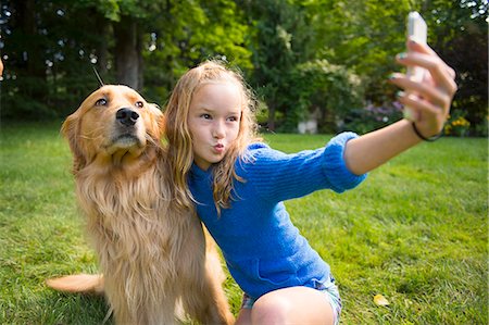 Girl taking selfie with pet dog in garden Foto de stock - Sin royalties Premium, Código: 614-07806458