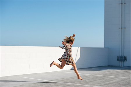 Girl jumping barefoot on building rooftop Foto de stock - Sin royalties Premium, Código: 614-07806535