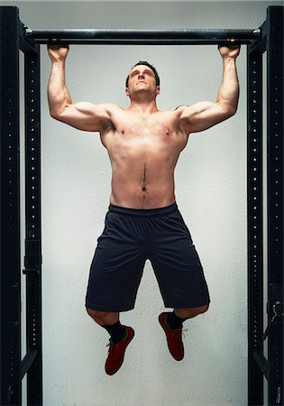 simsearch:649-03418414,k - Mid adult male doing pull ups on exercise bar in gym Fotografie stock - Premium Royalty-Free, Codice: 614-07806539