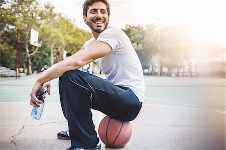 par-dessus l'épaule - Portrait of young male basketball sitting on ball Photographie de stock - Premium Libres de Droits, Code: 614-07911677