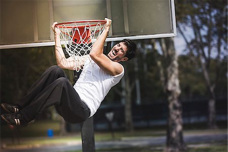 Young male basketball hanging from basketball hoop Photographie de stock - Premium Libres de Droits, Code: 614-07911678