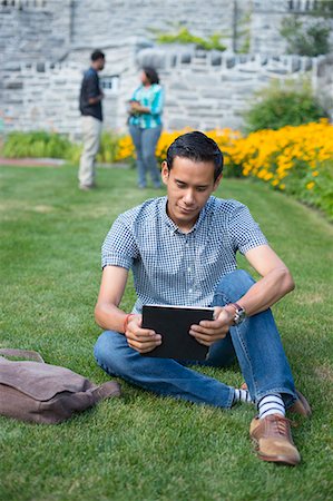 Male student sitting on grass using digital tablet Stock Photo - Premium Royalty-Free, Code: 614-07911711