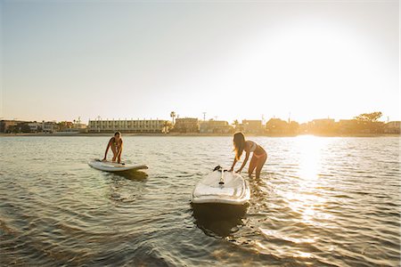 Two women pushing paddleboards at sunset, Mission Bay, San Diego, California, USA Photographie de stock - Premium Libres de Droits, Code: 614-07911744