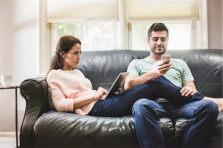 Couple using digital tablet and smartphone on sofa Stockbilder - Premium RF Lizenzfrei, Bildnummer: 614-07911825