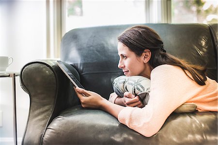 Woman using digital tablet on sofa Photographie de stock - Premium Libres de Droits, Code: 614-07911822