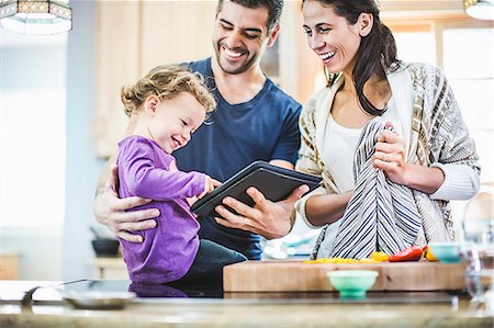 Parents and daughter using digital tablet in kitchen Stock Photo - Premium Royalty-Free, Code: 614-07911844