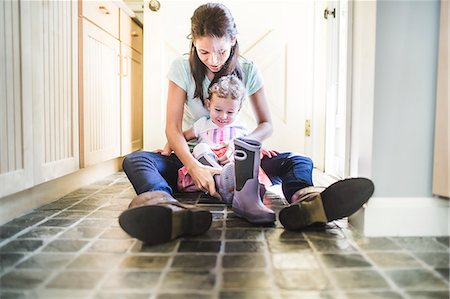 Mother and daughter putting on boots in kitchen Photographie de stock - Premium Libres de Droits, Code: 614-07911847