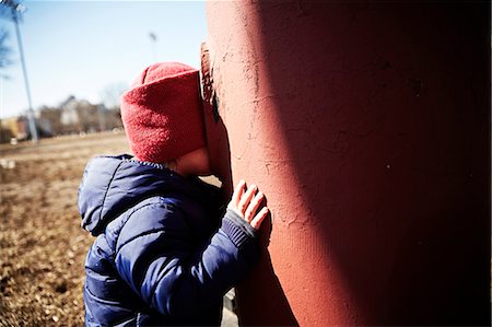 Male toddler playing hide and seek in park Stock Photo - Premium Royalty-Free, Code: 614-07911901