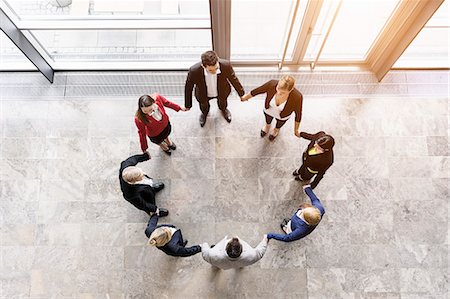 Overhead view of businessmen and women in circle holding hands Photographie de stock - Premium Libres de Droits, Code: 614-07911922