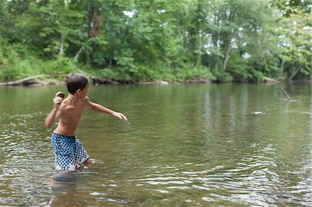 swim shorts for boys - Teenage boy skimming stones in river, Canton, North Carolina, USA Stock Photo - Premium Royalty-Free, Code: 614-07911999