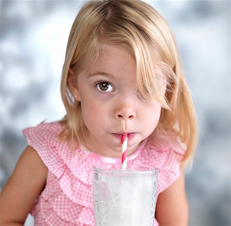 Portrait of female toddler blowing bubbles in milk through drinking straw Stock Photo - Premium Royalty-Free, Code: 614-07912023