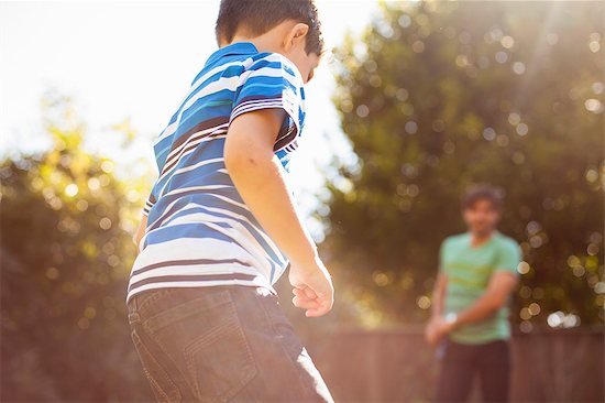 Father and son playing football in garden Stock Photo - Premium Royalty-Free, Image code: 614-08000137