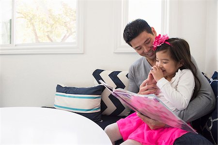 father teaching his child - Mature man and daughter reading storybook on sofa Photographie de stock - Premium Libres de Droits, Code: 614-08000339