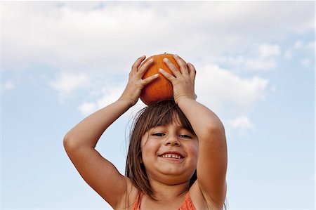 simsearch:649-07118498,k - Low angle portrait of girl holding up pumpkin on her head Photographie de stock - Premium Libres de Droits, Code: 614-08000397