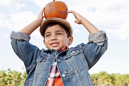 Low angle portrait of boy holding up pumpkin on his head Stock Photo - Premium Royalty-Free, Code: 614-08000398