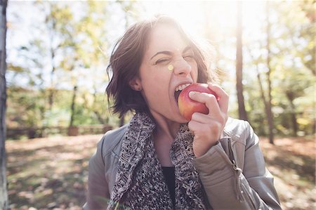 fruits - Young woman biting apple in forest Stock Photo - Premium Royalty-Free, Code: 614-08030473
