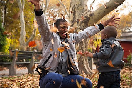 foglie d'autunno - Young man and toddler son throwing autumn leaves in park Fotografie stock - Premium Royalty-Free, Codice: 614-08030487