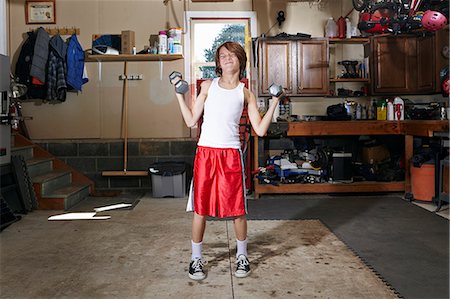 fitness home - Slim boy struggling to lift hand weights in garage Foto de stock - Sin royalties Premium, Código: 614-08030628