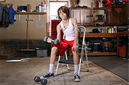 power child - Slim boy struggling to lift hand weight in garage Stock Photo - Premium Royalty-Free, Code: 614-08030629