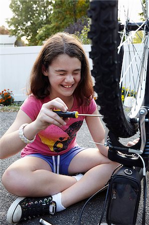 repaired - Laughing girl repairing bicycle on driveway Photographie de stock - Premium Libres de Droits, Code: 614-08030635