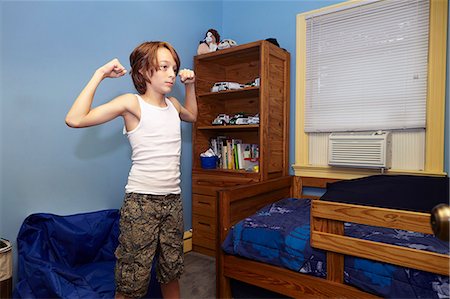 Slim boy flexing arm muscles in bedroom Foto de stock - Sin royalties Premium, Código: 614-08030631