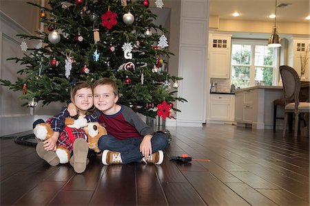 Portrait of brother with arm around sister in front of xmas tree Stock Photo - Premium Royalty-Free, Code: 614-08030658